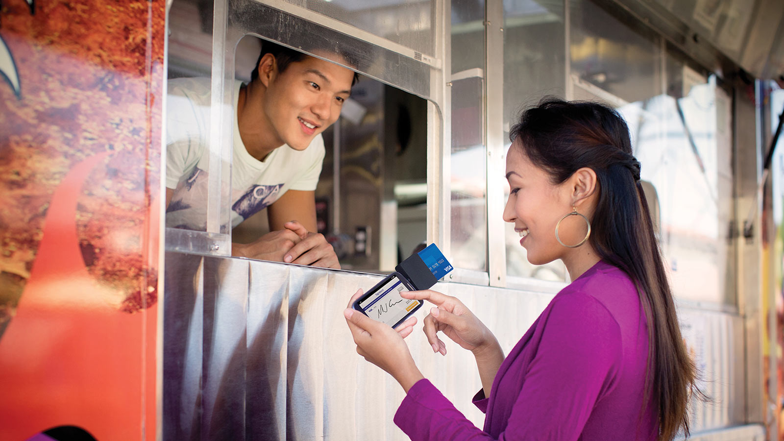 Woman using a mobile card reader to make purchase at food truck.